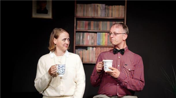 Ein Mann und eine Frau trinken auf der Bühne einen Kaffee.