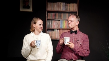 Ein Mann und eine Frau trinken auf der Bühne einen Kaffee.