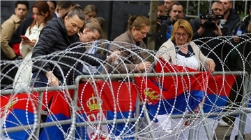 Frauen befestigen serbische Flaggen an einem Zaun vor dem Rathaus während einer Demonstration in der Stadt Zvecan im Norden des Kosovo.