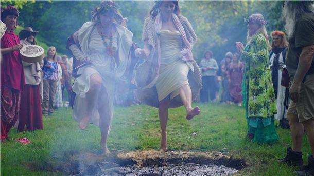Frauen springen beim Beltane-Festival am Glastonbury Chalice Well in England über das Feuer.