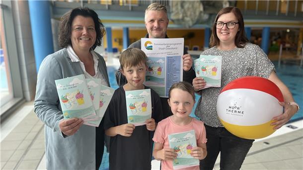 Zwei Frauen, ein Mann und zwei Kinder stehen in einem Schwimmbad.