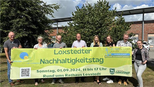 Acht Männer und Frauen halten ein Plakat mit der Aufschrift "Loxstedter Nachhaltigkeitstag" in die Kamera.