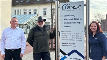 Zwei Männer und eine Frau stehen vor dem Sitz der Gemeinnützigen Nordenhamer Siedlungsgesellschaft (GNSG).