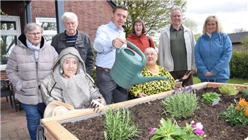 Acht Personen stehen oder sitzen an einem neuen Hochbeet im Seniorenheim To Huus achtern Diek in Nordenham-Blexen.