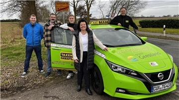 vier Menschen am grünen Taxi