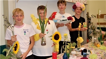 Vier Schüler präsentieren ihre Ergebnisse aus der Blumenwerkstatt.