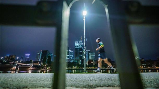 Frühsport in der Banken-Stadt: Ein Jogger läuft am frühen Morgen vor der Skyline von Frankfurt am Main.