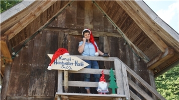 Eine Frau mit einer Nikolausmütze steht auf einem Treppenaufgang und telefoniert.