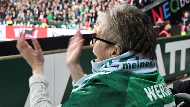 Frau jubelt im Stadion bei einem Fußballspiel mit.