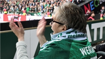 Frau jubelt im Stadion bei einem Fußballspiel mit.