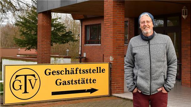 Ein Mann steht vor einem Haus und einem Schild. 