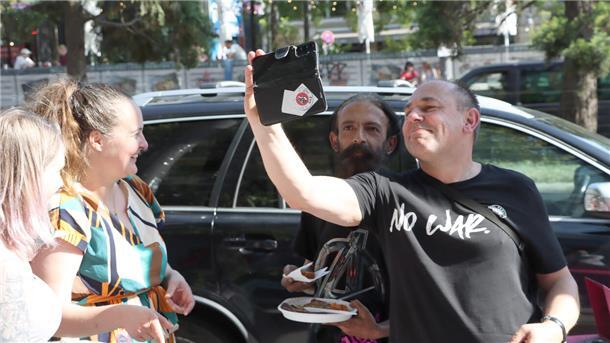 Ein Mann macht ein Selfie von sich und einem anderen Mann während zwei Frauen zuschauen.