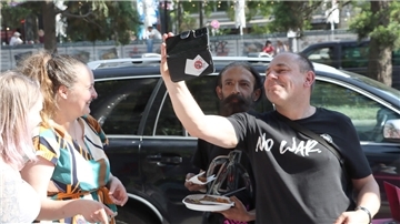 Ein Mann macht ein Selfie von sich und einem anderen Mann während zwei Frauen zuschauen.