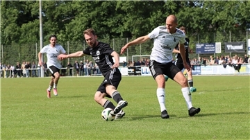Zwei Männer in Sporttrikots kämpfen um einen Ball.