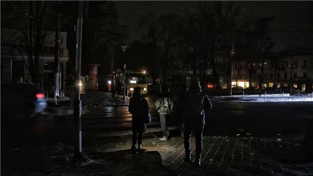 Ukraine: „Alle Wärme- und Wasserkraftwerke“ beschädigt Fußgänger halten sich in Odessa an einer Kreuzung auf einer dunklen Straße auf, da die Stadt von Stromausfällen betroffen ist.
