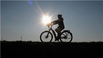 Gegen die Sonne fotografiert sieht man die Silhouette eines Fahrradfahrers.