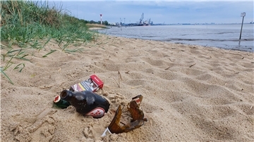 Glasflaschen und eine Zigarettenschachtel liegen in Nordenham am Weserstrand.
