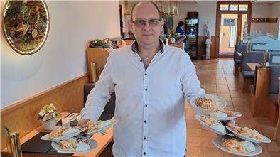 Gelernt ist gelernt: Georgius Stavrakoudis balanciert in seinem neuen griechischen Restaurant „Hellas“ in Lunestedt acht Tellern mit Bohnen- und Krautsalat sowie Tzatziki. 