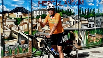 Ein Mann auf einem Rennrad vor einem bunten Wandbild.