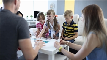 Kinder und Erwachsene spielen ein Brettspiel.