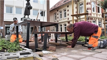 Gezielte Hammerschläge müssen schon sein, damit die Steine auch korrekt sitzen: Ralf Grawitter (rechts) und David Eva sorgen für die Standsicherheit der neuen Sitzkombination am Rathaus in Bad Bederkesa