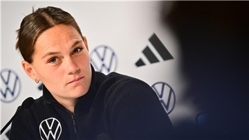 Eine Fußballerin hört sich bei einer Pressekonferenz die nächste Frage der Journalisten an.