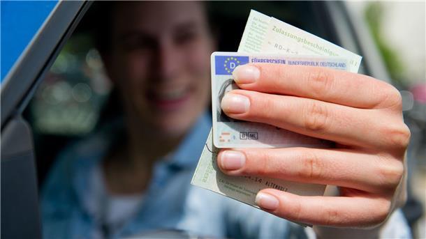 Eine Frau hält ihre Papiere aus dem Auto