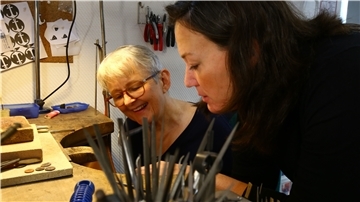 Goldschmiedin Constanze Kuschel (rechts) erklärt Redakteurin Ellen Reim, wie ein Sägeblatt eingespannt wird. Von den Blättern verbraucht die Anfängerin jede Menge.