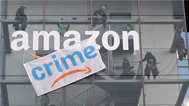 Greenpeace-Aktive hängen während der Rabattaktion Black Friday ein Plakat gegen die Ressourcenverschwendung des Online-Versandhändlers Amazon an dessen Gebäude in München auf.
