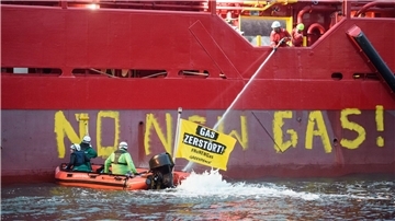 Greenpeace-Aktivisten mit einem Schlauchboot vor einem Schiff im Hafen von Mukran.