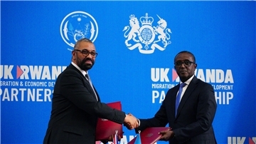 Großbritanniens Innenminister James Cleverly (l) und Vincent Birut, Außenminister von Ruanda, schütteln sich die Hände. Mit dem neuen Vertrag will die britische Regierung Asylsuchende künftig in das ostafrikanische Land abschieben.