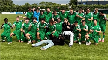 Eine Fußballmannschaft steht auf dem Rasen zum Gruppenfoto zusammen und ballt die Siegerfaust.