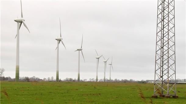 Das Foto zeigt links sechs Windräder und rechts einen Strommast.