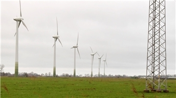 Das Foto zeigt links sechs Windräder und rechts einen Strommast.