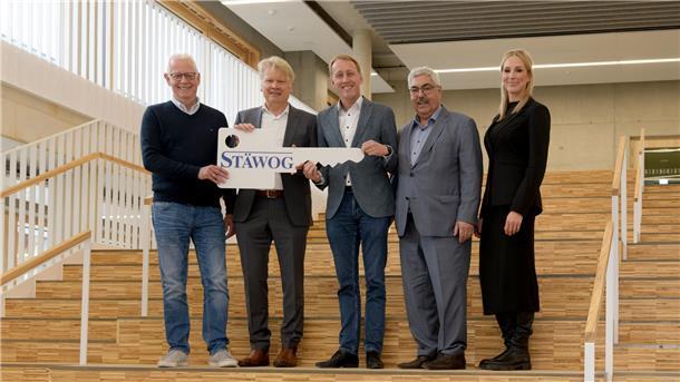 Menschen auf einer Treppe, die einen übergroßen Schlüssel halten.