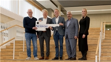 Menschen auf einer Treppe, die einen übergroßen Schlüssel halten.