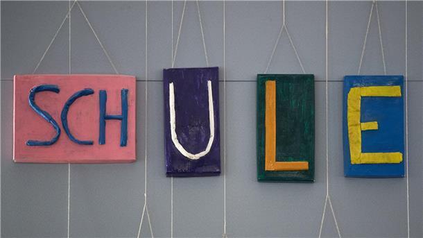 Bunte Buchstaben hängen an der Wand. Sie zeigen das Wort Schule.
