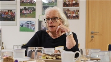 Frau mit schwarzem Pullover an Kaffeetafel