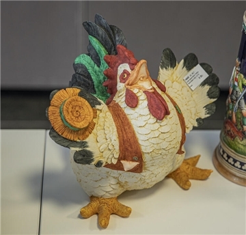 Porzellan-Henne mit Hut und breitem Grinsen.