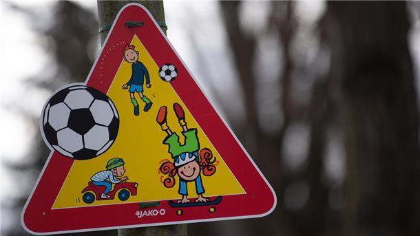 Ein Warnschild weist vor einem Kindergarten auf spielende Kinder hin.