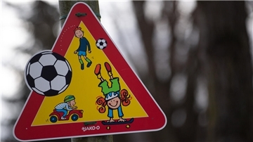Ein Warnschild weist vor einem Kindergarten auf spielende Kinder hin.