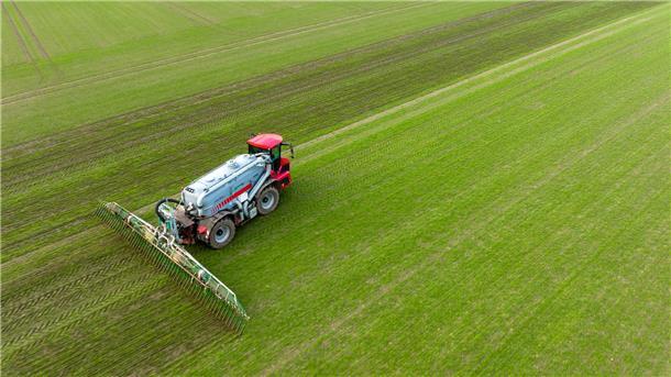 Ein Landwirt bringt mit seinem Gespann Gülle im sogenannten Schleppschuh Verfahren auf einem Feld aus