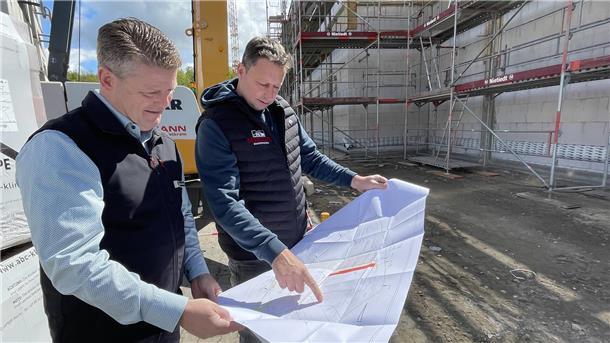 Zwei Männer studieren auf einer Baustelle einen Plan. Das E-Center in Nordenham erhält einen Anbau. 