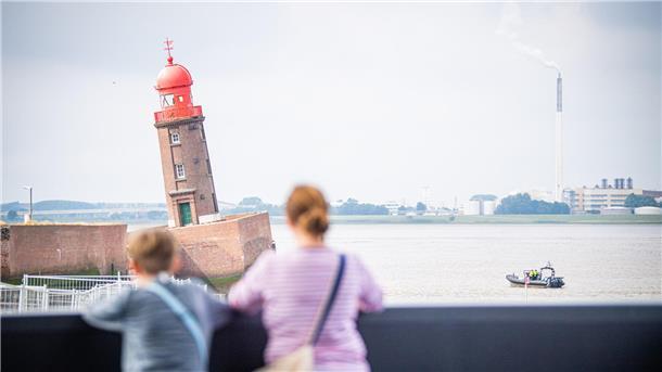 Zwei Menschen blicken auf den schiefen Molenturm.