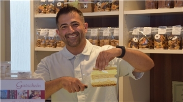 Hamza Atilgan hält ein Stück Kuchen in der Hand. 