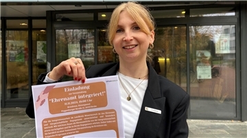 Hannah Sophie Heldberg hält ein Plakat für die Veranstaltung "Ehrenamt integriert" hoch