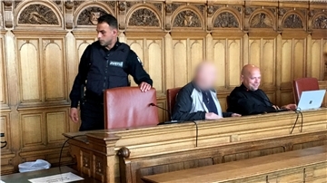 Angeklagte mit Anwalt auf einer Bank. 