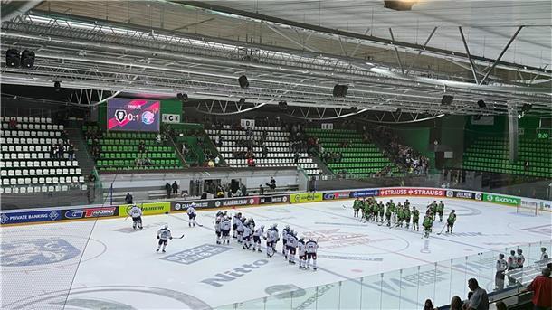 Blick in eine Eisarena, fast leere Ränge und Spieler.