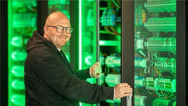 Mann vor grün leuchtenden Schaltkästen