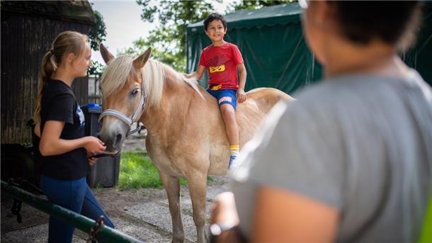 Der kleine Noah sitzt zum ersten Mal auf dem Rücken eines Pferdes, beaufsichtigt von Schülerin Fiona. Sie betreut den alten Haflinger 'Felix'.